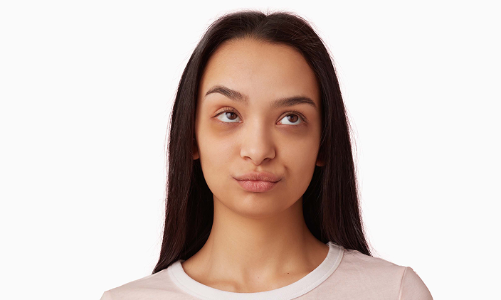teenage-girl-annoyed-looking-woman-with-dark-long-hair-wearing-white-t-shirt-people-emotion-concept-rolls-her-eyes-pursed-lips-watching-up-copy-space-isolated-pink-wall 1
